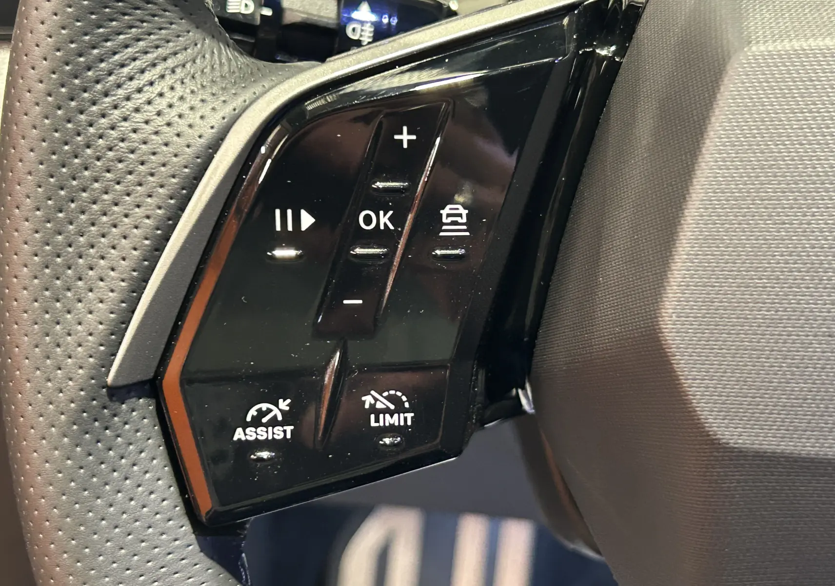 Gros plan sur les commandes du volant à gauche du Peugeot 3008 bleu Obsession, avec boutons de régulateur et limiteur de vitesse.