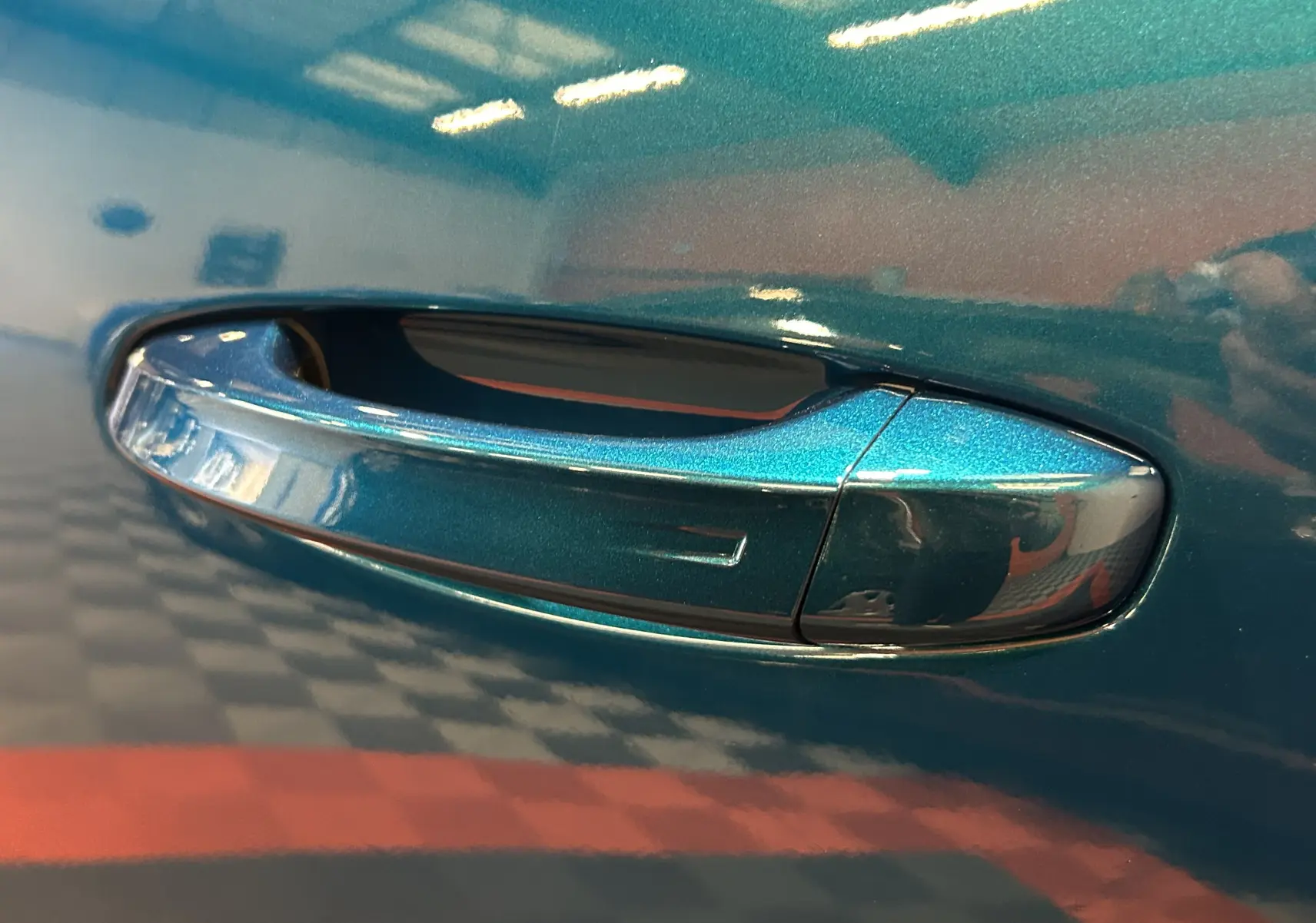 Poignée de porte côté gauche en gros plan sur Peugeot 3008 III Hybrid 145 bleu obsession avec finition brillante.