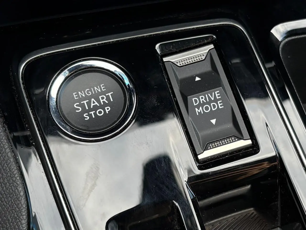 Gros plan sur la console centrale noire brillante du Peugeot 3008 GT 2023 avec bouton start/stop et commande Drive Mode.