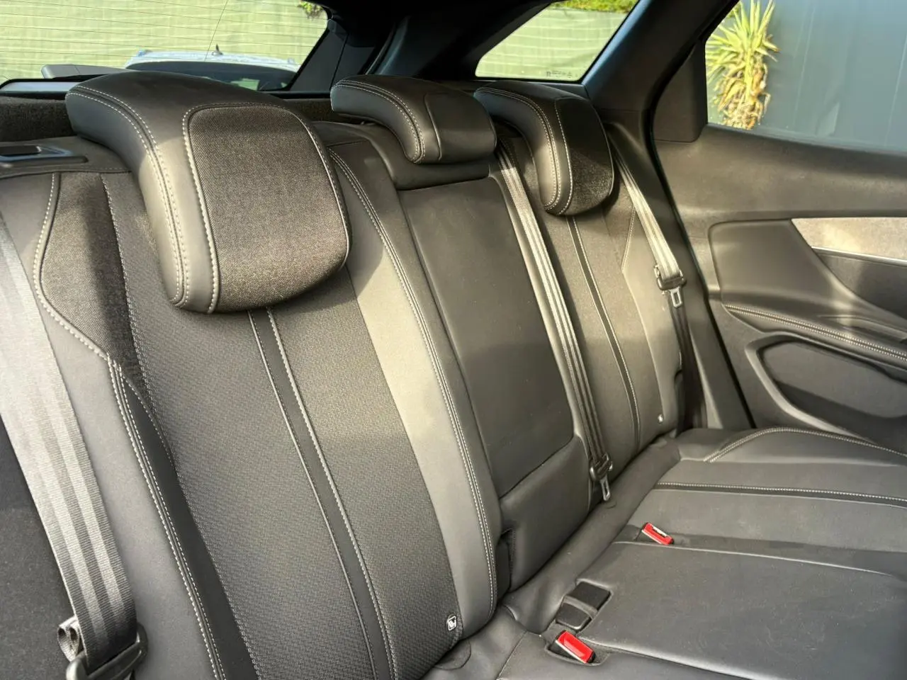 Vue intérieure de la banquette arrière noire du Peugeot 3008 2023 avec ceintures et appuie-têtes intégrés.
