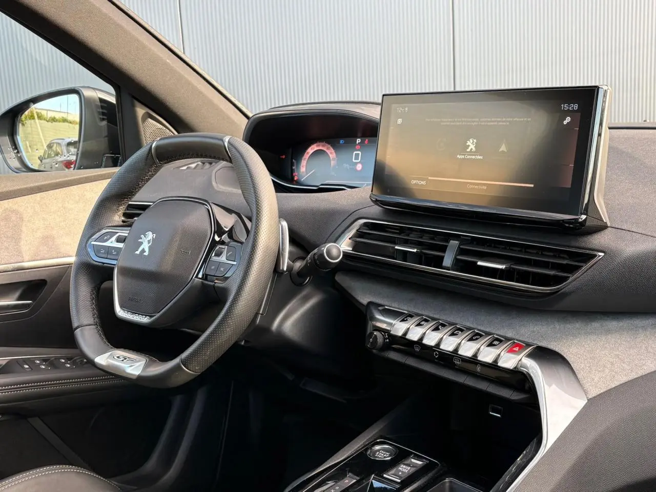 Intérieur avant droit du Peugeot 3008 GT 2023, volant cuir perforé et écran tactile 10 pouces allumé.