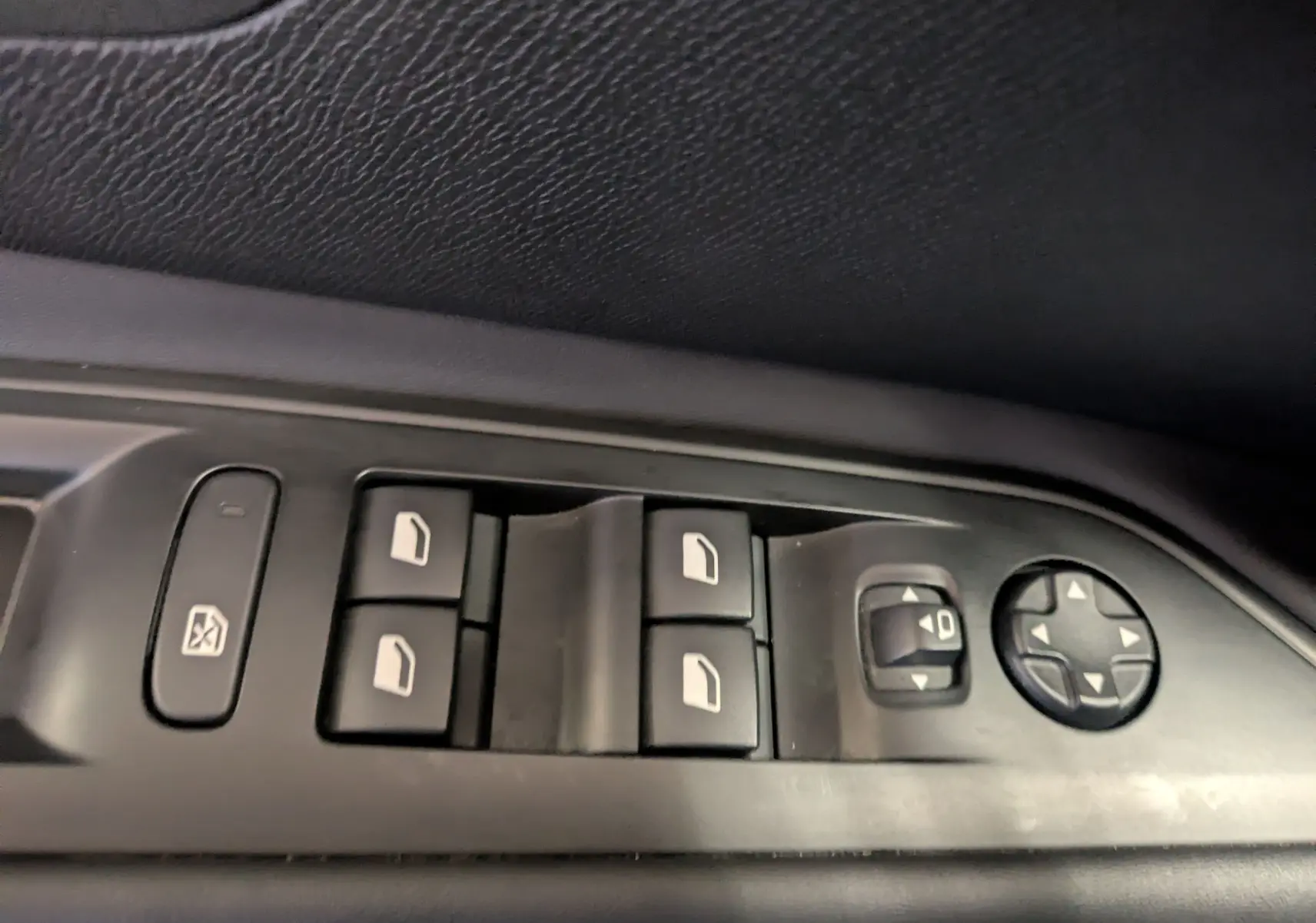 Gros plan sur les commandes de lève-vitres et réglage des rétroviseurs côté conducteur d’un Peugeot 5008 noir 2024.
