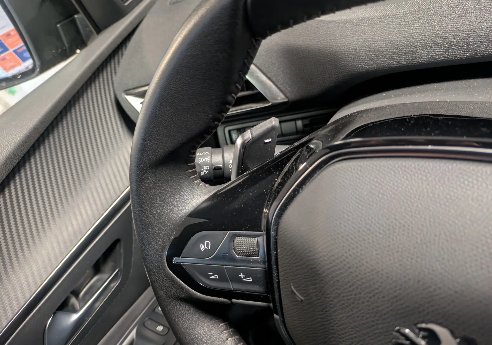 Gros plan sur le volant cuir noir du Peugeot 5008 2024, avec commandes intégrées et tableau de bord partiel visible.