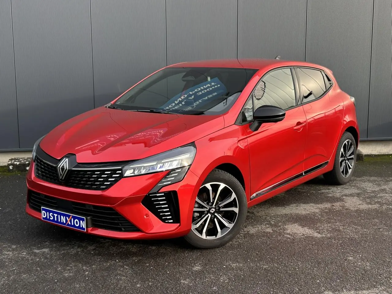 Renault Clio Rouge Désir vue 3/4 avant droit, avec jantes alliage et rétroviseurs noirs contrastants.
