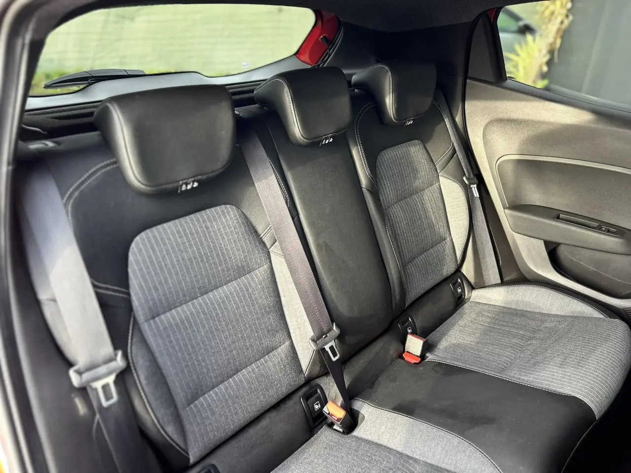 Vue intérieure côté droit sur la banquette arrière grise et noire de la Renault Clio 2025, avec ceintures de sécurité visibles.