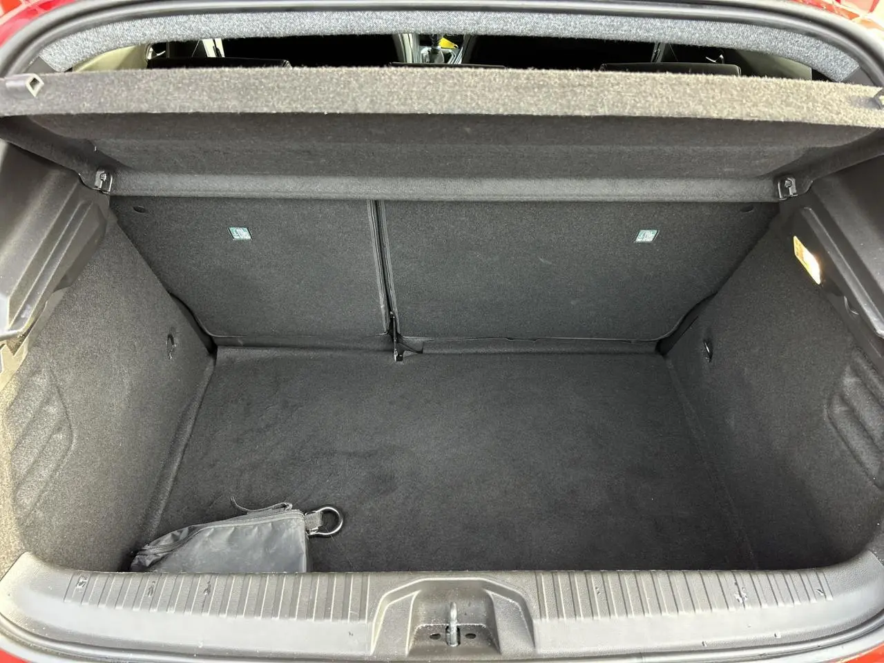 Coffre ouvert de la Renault Clio Rouge Désir 2025, vue intérieure montrant l'espace de rangement vide et tapis noir.