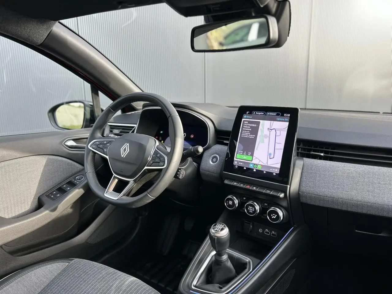 Vue intérieure côté conducteur de la Renault Clio 2025 avec tableau de bord moderne et écran tactile vertical GPS.