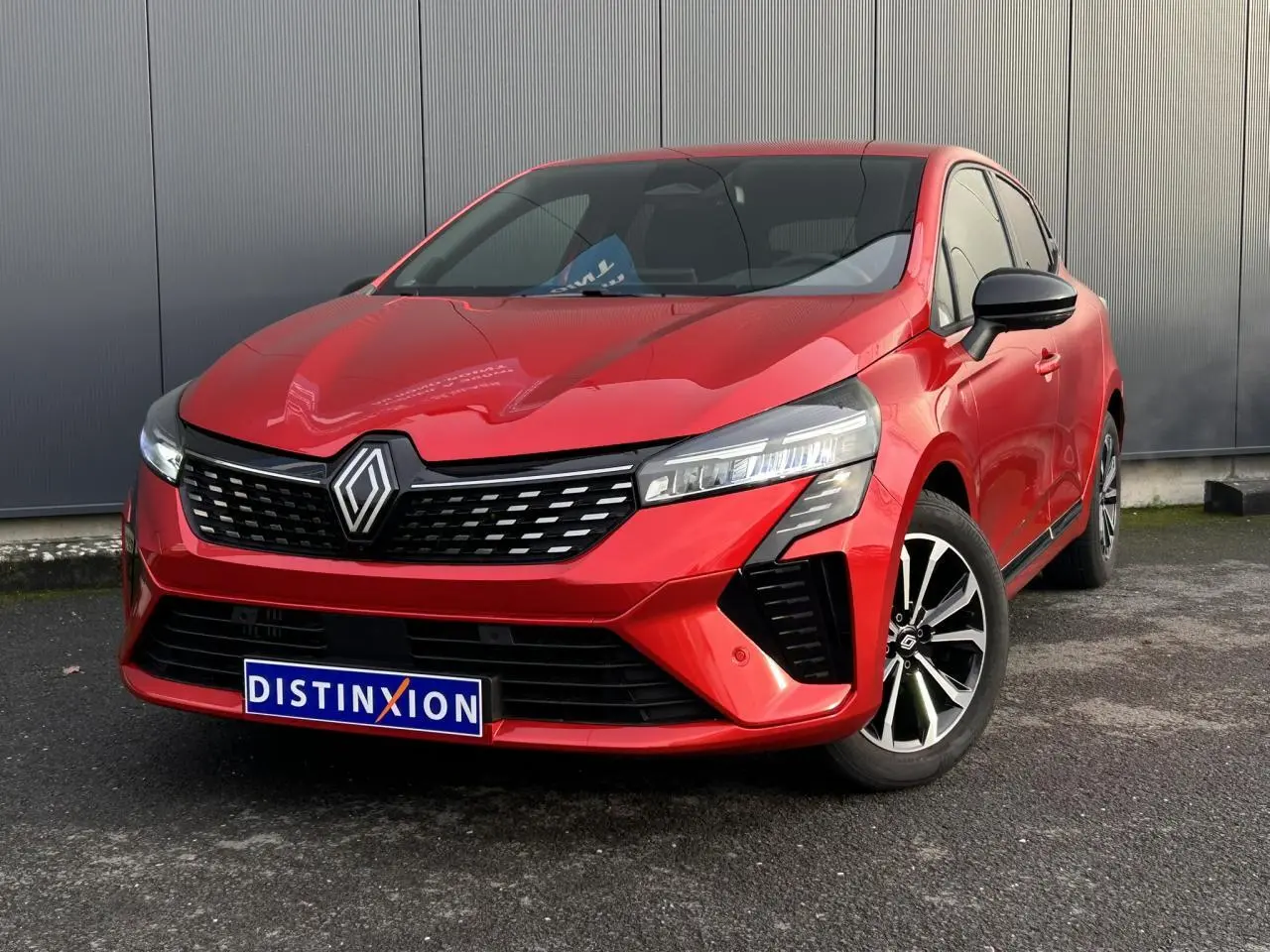 Renault Clio 2025 Rouge Désir vue 3/4 avant droit, avec calandre noire et jantes alliage diamantées.