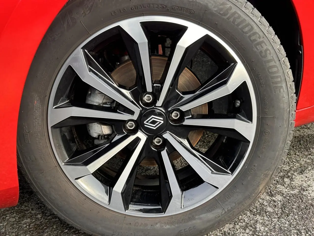 Gros plan sur la jante alliage diamantée 16" noire et argentée d'une Renault Clio Rouge Désir.