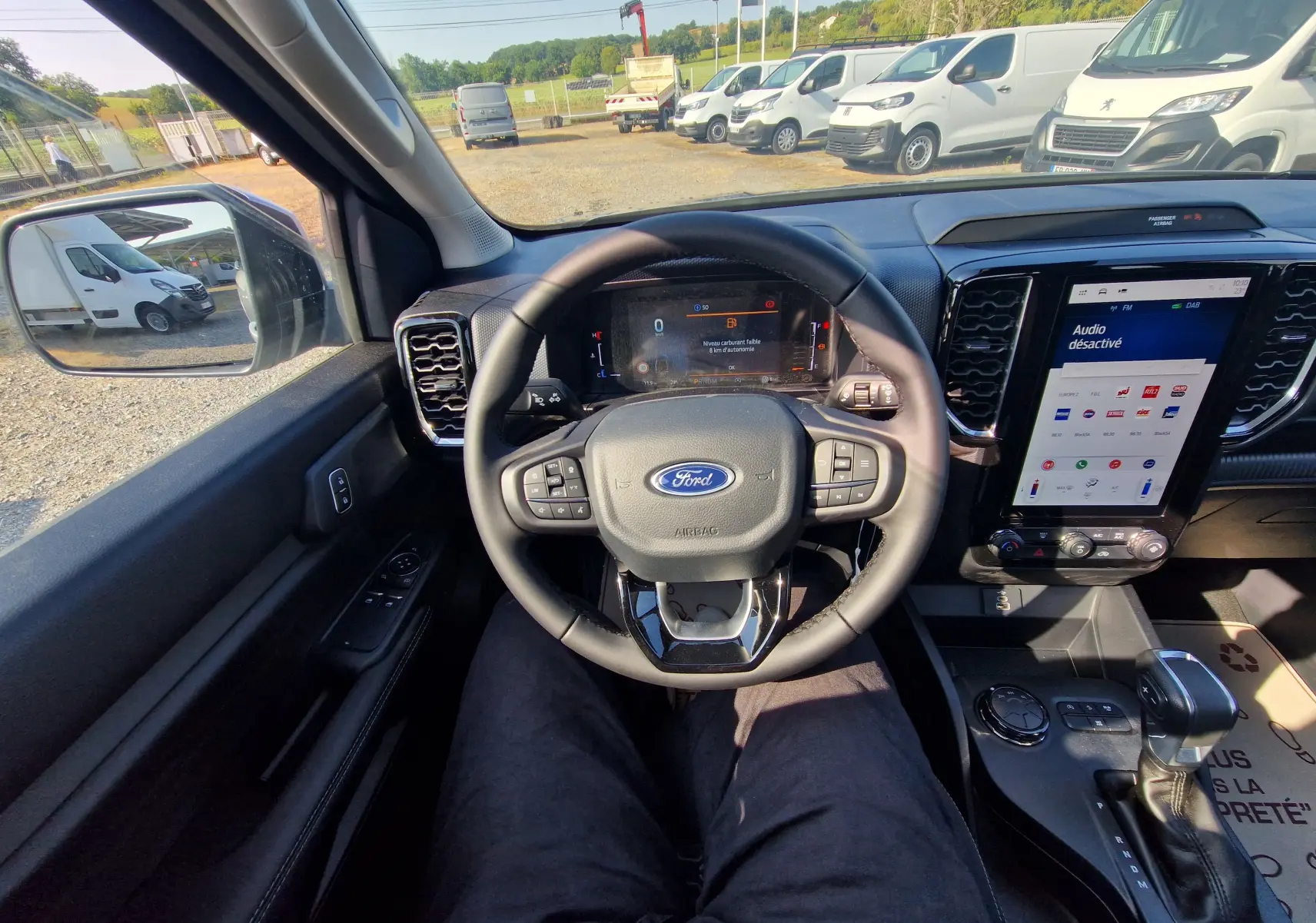 Vue intérieure côté conducteur du Ford Ranger Super Cabine gris Iconic, mettant en valeur le volant multifonction et l'écran tactile central.