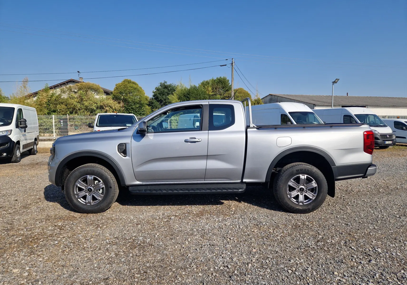 Ford Ranger Super Cabine gris Iconic vu de profil côté gauche, avec roues tout-terrain et arceau arrière.