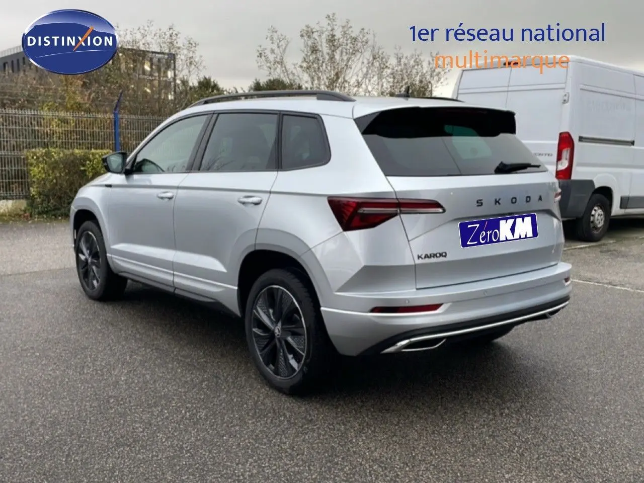 Vue 3/4 arrière d'un Skoda Karoq gris argent métallisé avec jantes noires et feux arrière LED distinctifs.
