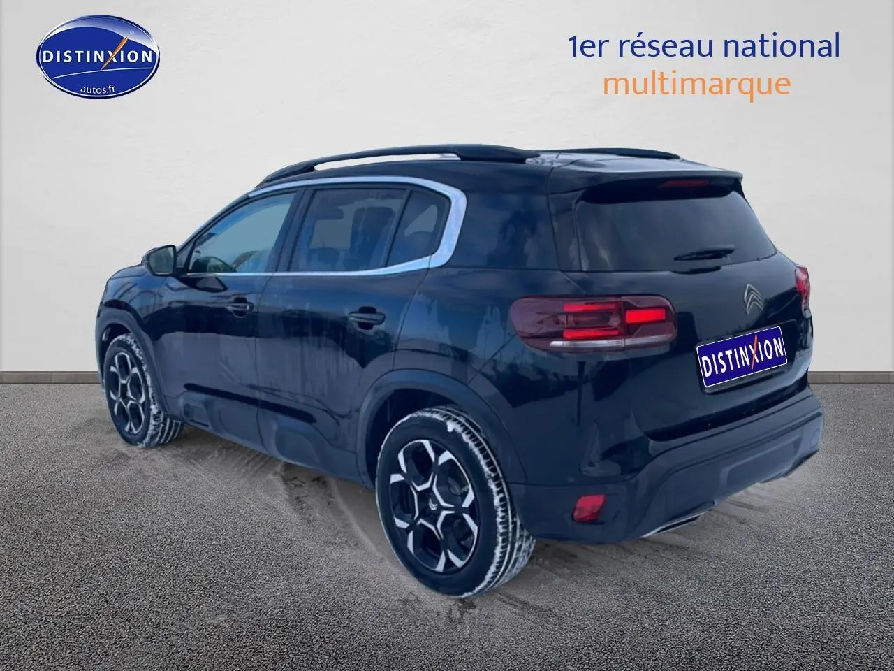 Vue 3/4 arrière droite d’un Citroën C5 Aircross noir 2025 avec jantes alu et barres de toit visibles.