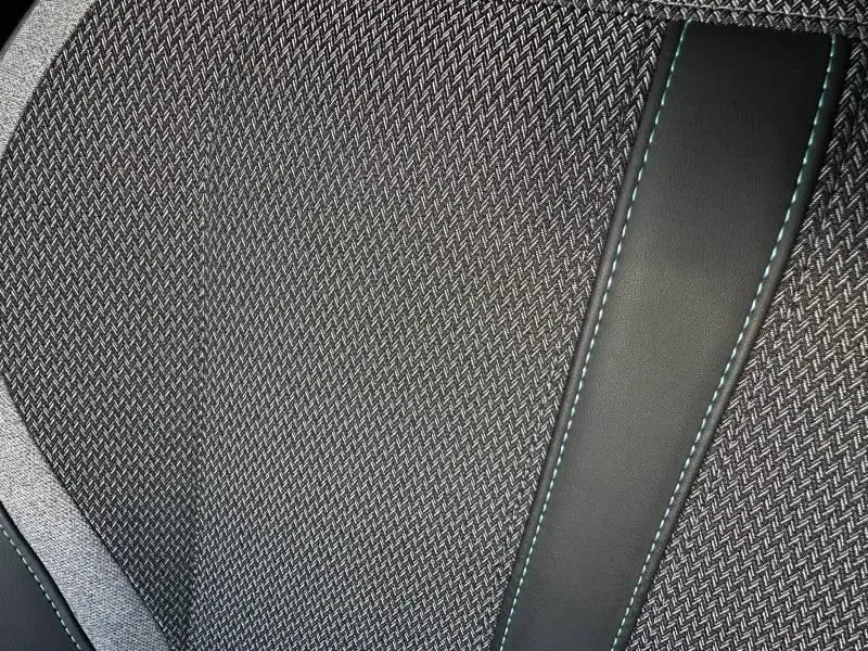 Gros plan sur la texture du tissu gris et les surpiqûres bleues du siège avant du Peugeot 308 SW Rouge Elixir 2024.