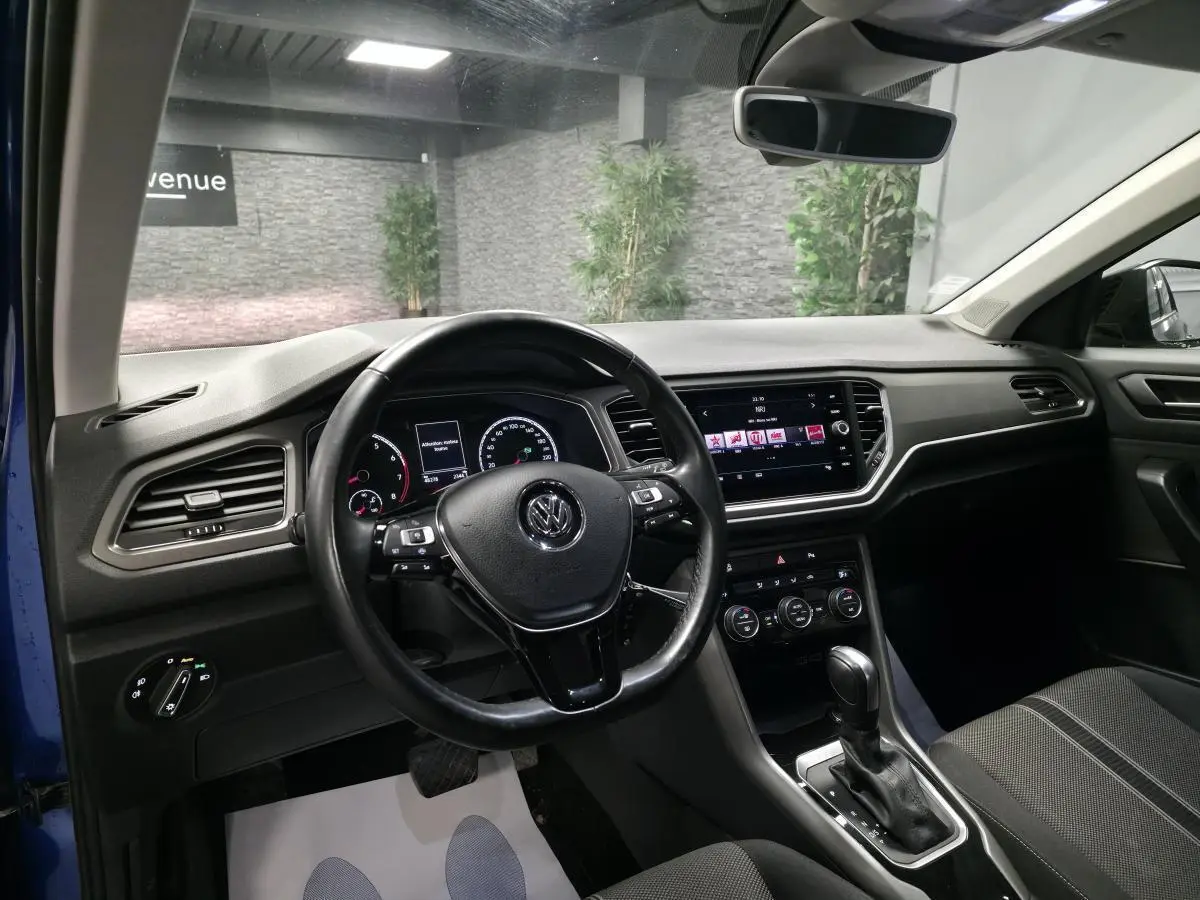 Intérieur du Volkswagen T-Roc bleu foncé, vue côté conducteur, volant cuir multifonction et tableau de bord digital.