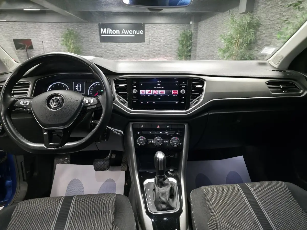 Vue intérieure avant du Volkswagen T-Roc 1.5 TSI Evo 2020, tableau de bord noir avec écran tactile central et volant multifonction.