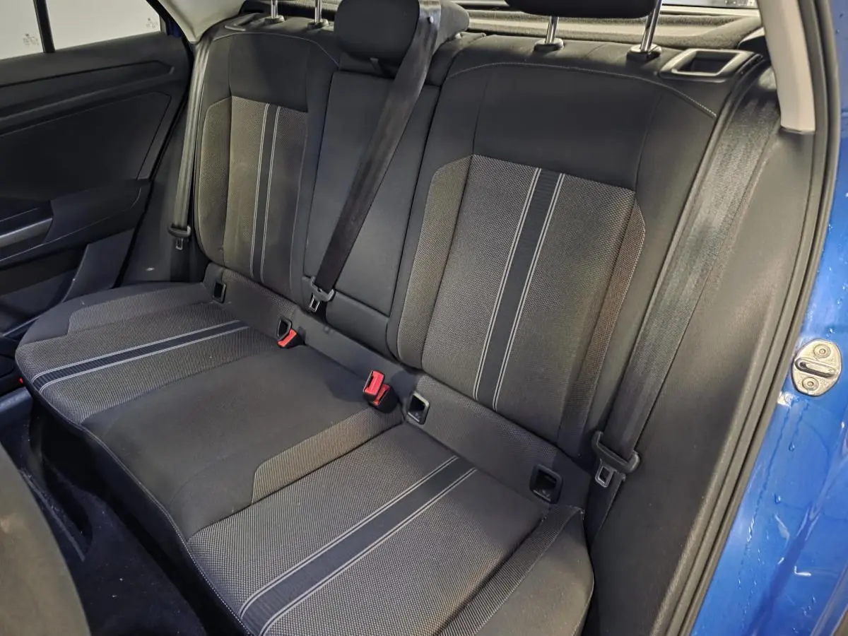 Vue intérieure du siège arrière côté droit du Volkswagen T-Roc bleu foncé, avec ceintures de sécurité et tissu noir à motifs gris.