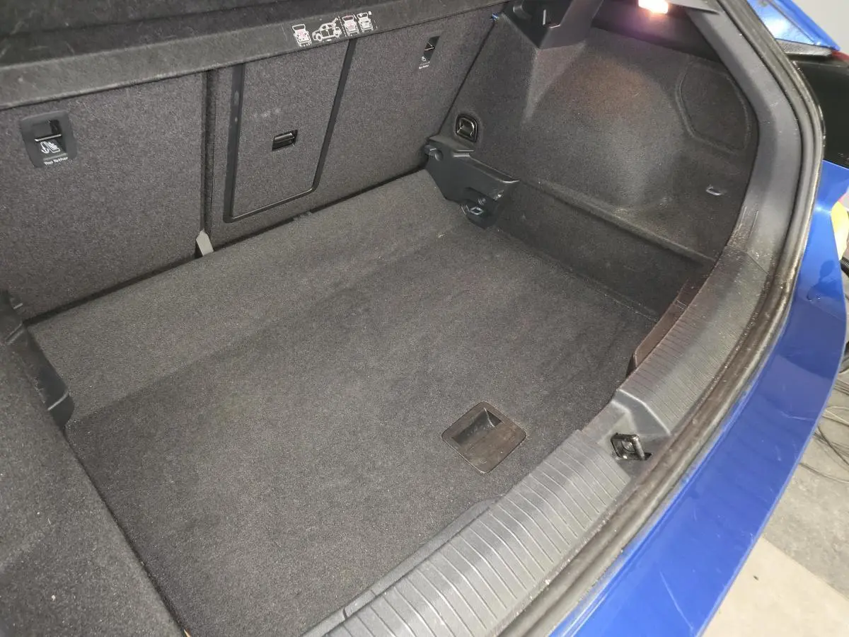 Vue intérieure du coffre spacieux d'un Volkswagen T-Roc bleu foncé, montrant la moquette noire et les fixations ISOFIX.