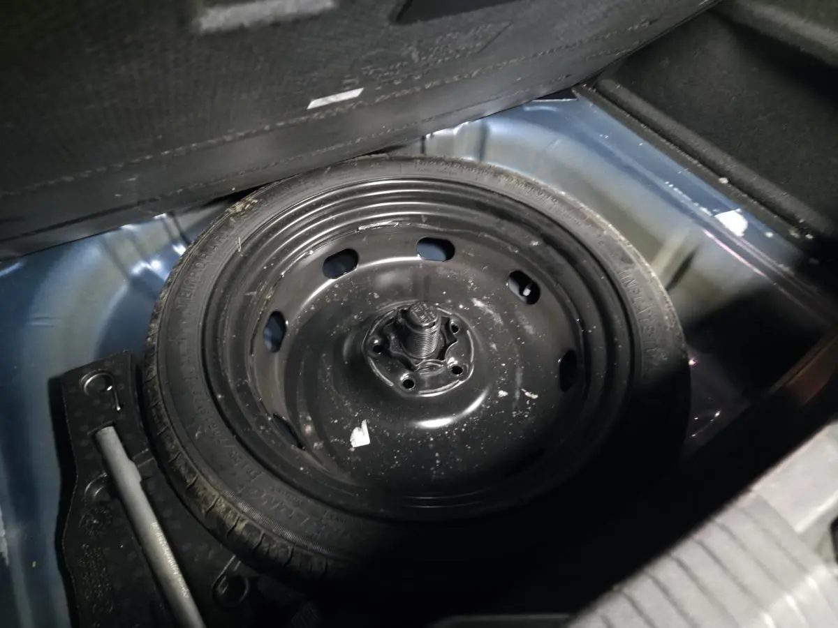 Gros plan sur la roue de secours noire dans le coffre bleu foncé du Volkswagen T-Roc 1.5 TSI Evo 2020.