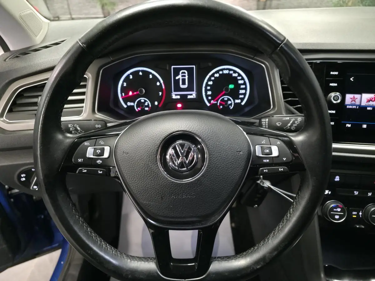 Vue centrée sur le volant en cuir noir et le tableau de bord numérique du Volkswagen T-Roc bleu foncé 2020.