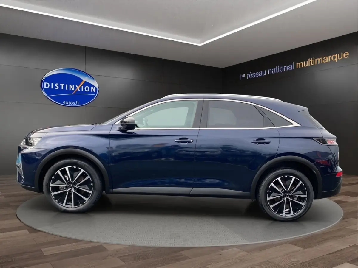 Vue latérale droite d'un DS7 Crossback bleu 2024 avec jantes alliage noires et toit argenté en showroom.