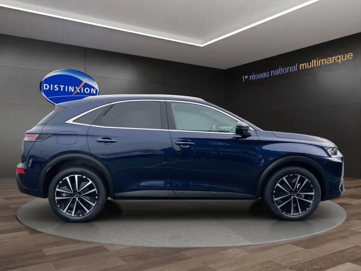 Vue latérale droite du DS7 Crossback bleu 2024 avec jantes alliage et toit chromé dans un showroom.