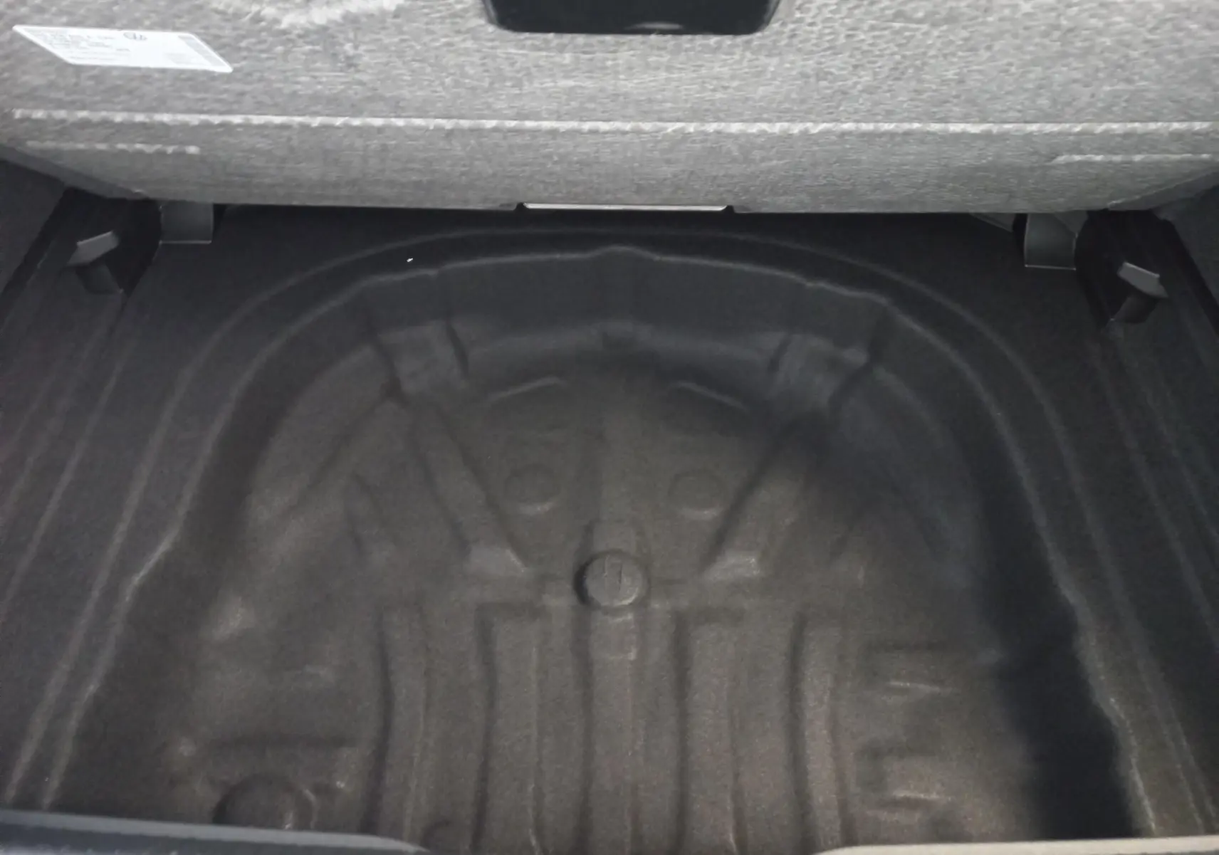 Coffre ouvert en vue plongeante d'une Volkswagen Golf 1.5 eTSI 150 DSG7 R-Line Edition noir ébène, sans roue de secours visible.