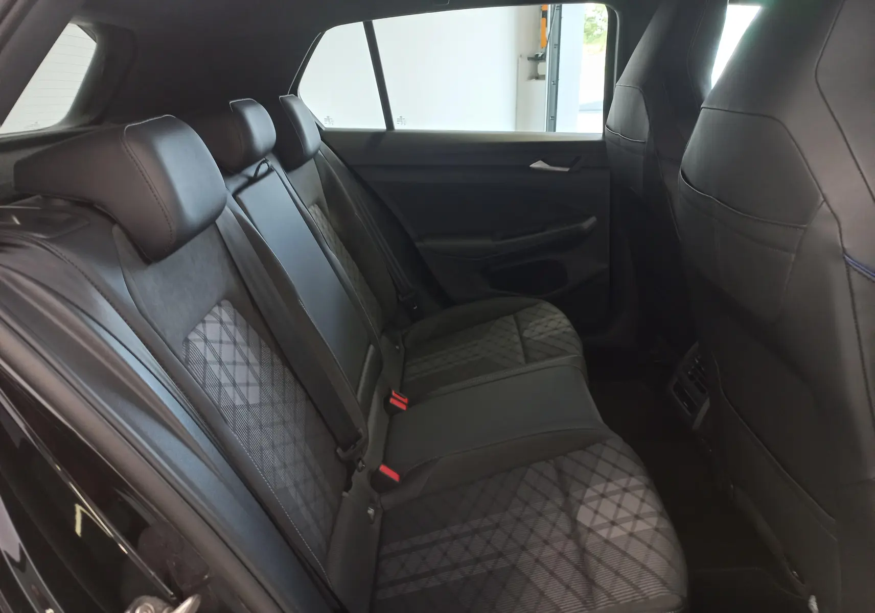 Vue intérieure arrière côté droit de la Volkswagen Golf 1.5 eTSI R-Line Edition 2025 avec sièges en tissu noir à motif géométrique.
