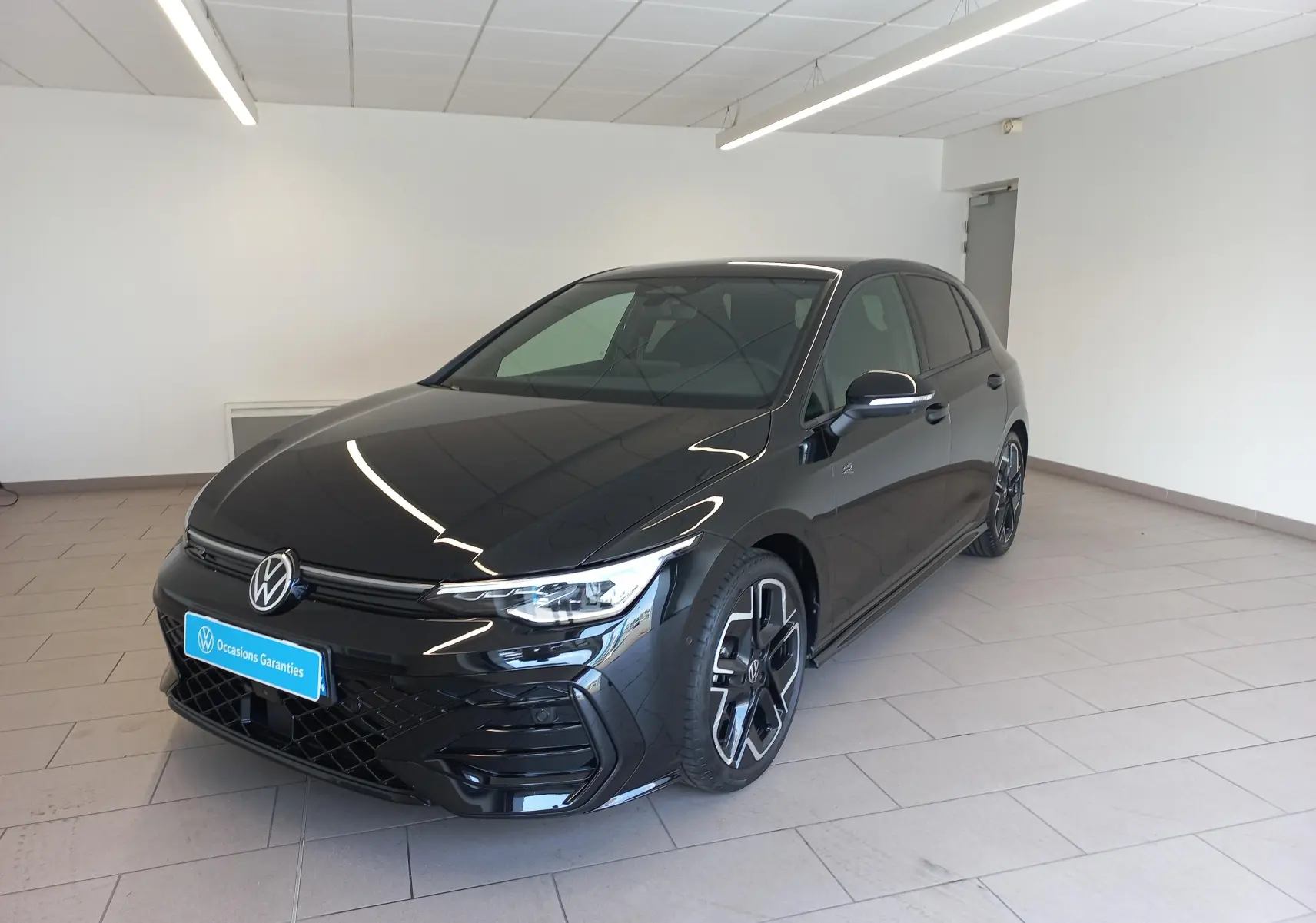 Volkswagen Golf 1.5 eTSI R-Line noir Ébène vue 3/4 avant droit en intérieur avec jantes distinctives.