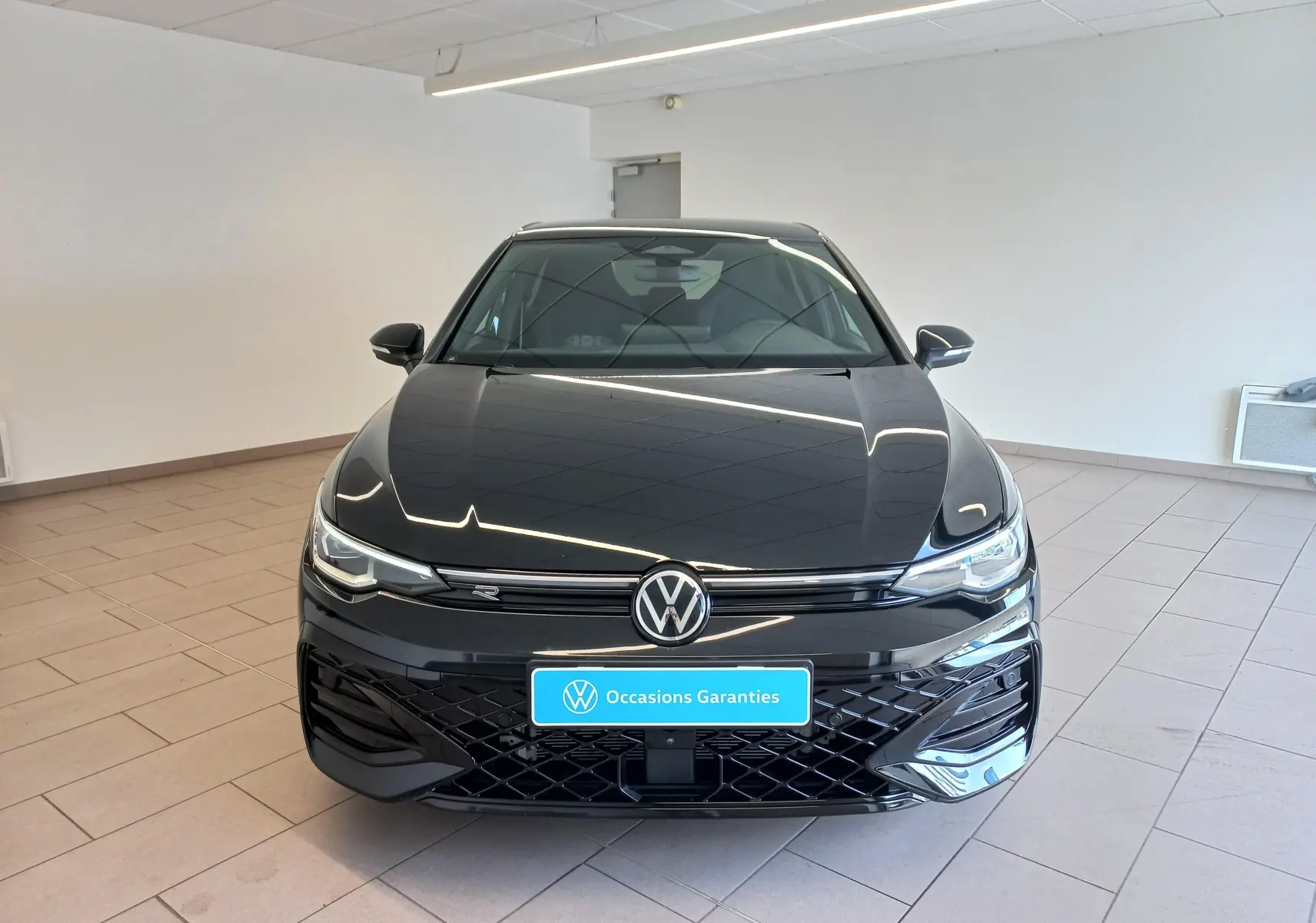 Volkswagen Golf 1.5 eTSI R-Line Edition noir Ébène vue de face en intérieur avec calandre et logo distinctifs.