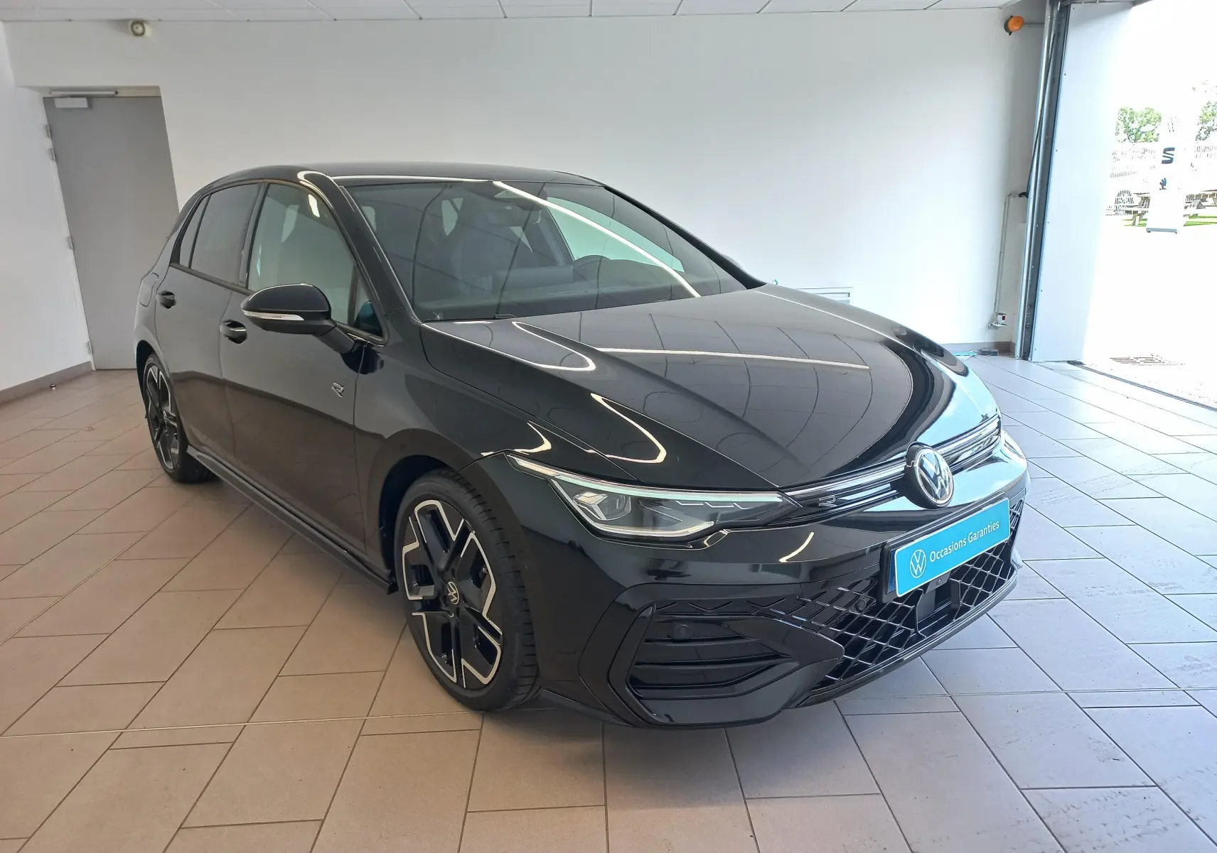 Volkswagen Golf 1.5 eTSI 150 DSG7 R-Line Edition noir ébène vue 3/4 avant en intérieur avec jantes noires distinctives.