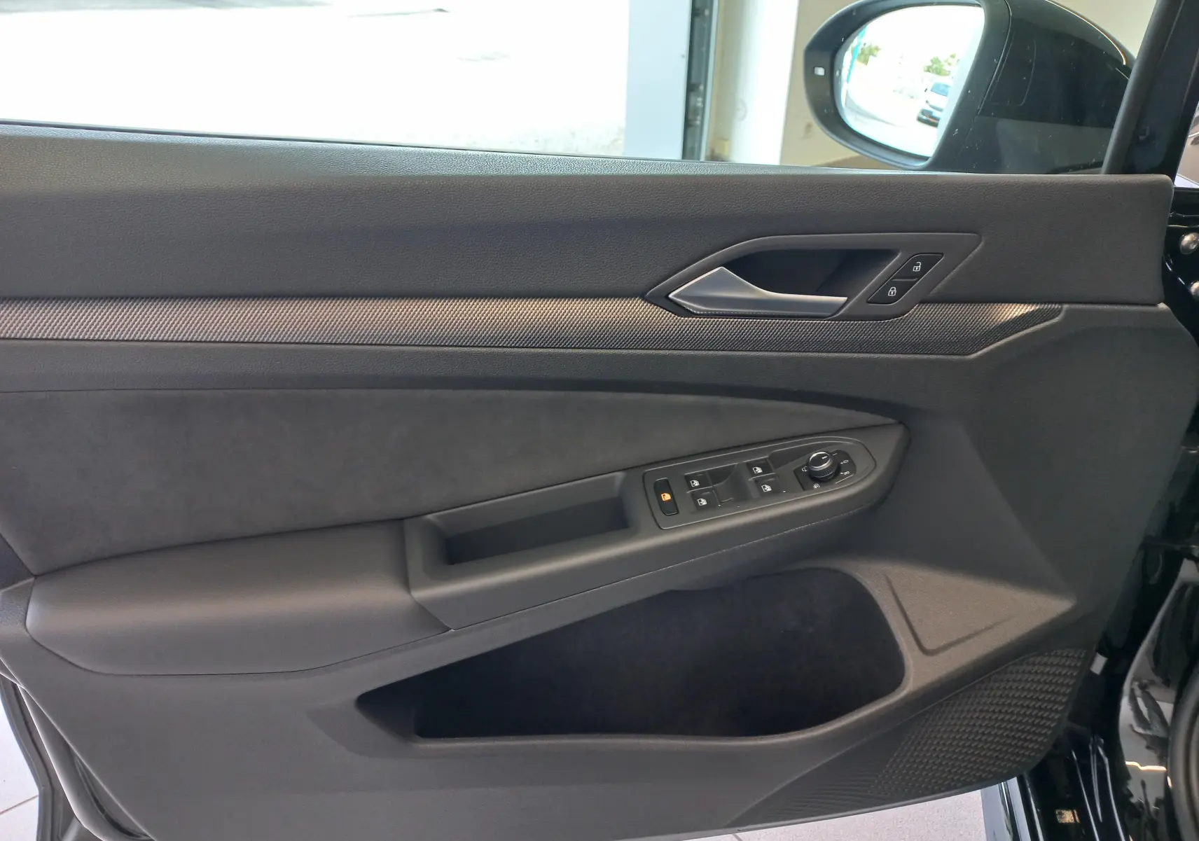 Vue intérieure de la porte côté gauche de la Volkswagen Golf 1.5 eTSI R-Line 2025 en noir ébène avec commandes électriques.