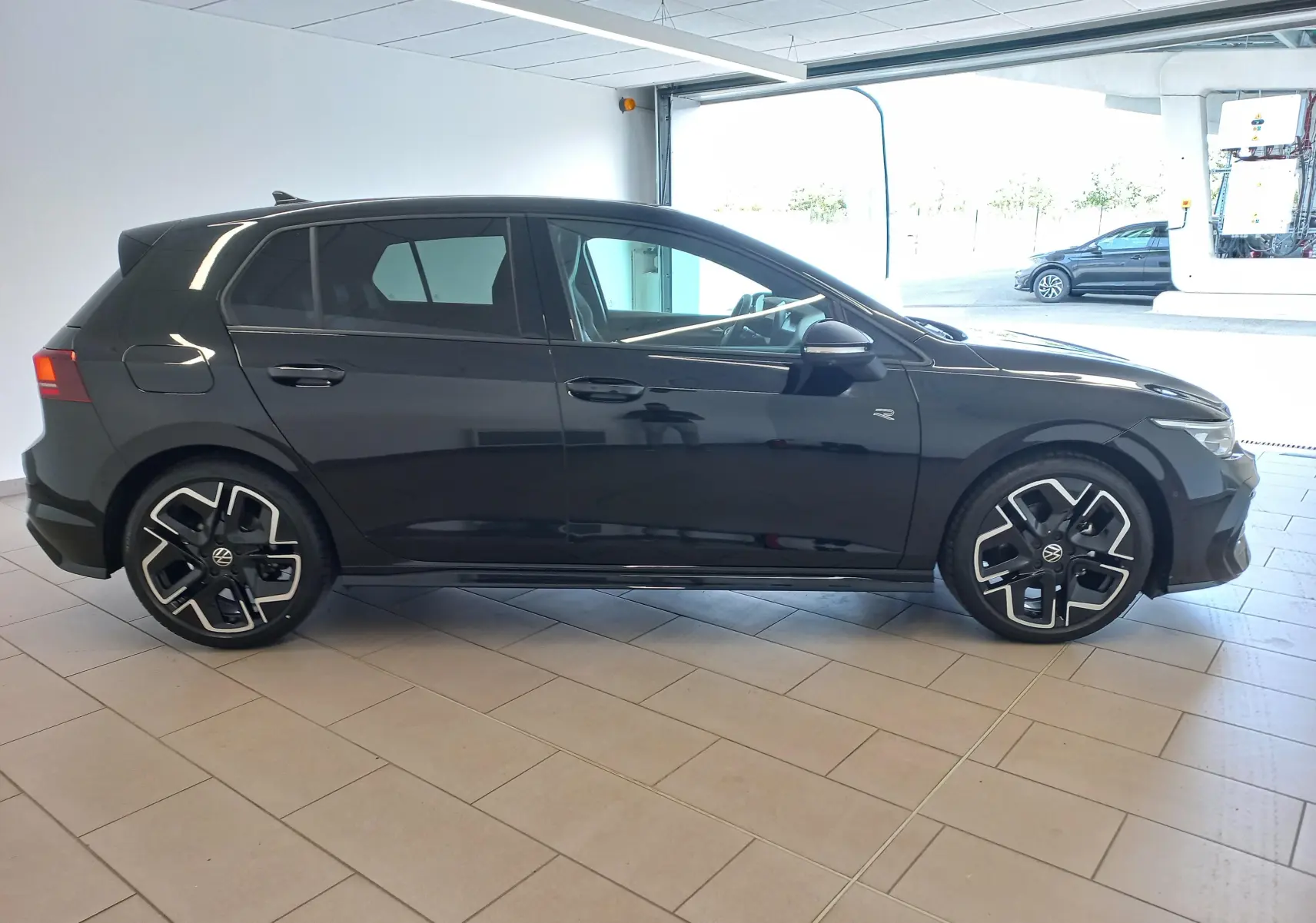 Volkswagen Golf 1.5 eTSI R-Line noir Ébène vue de profil côté gauche en intérieur, jantes alliage distinctives.