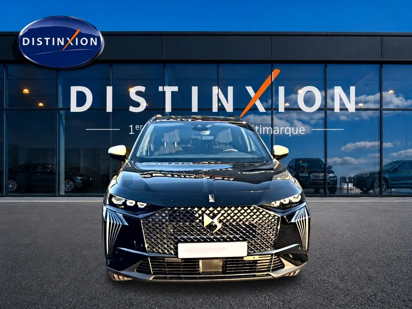Vue de face du DS7 noir 2026 avec sa calandre distinctive et ses phares LED, devant une vitrine Distinxion.
