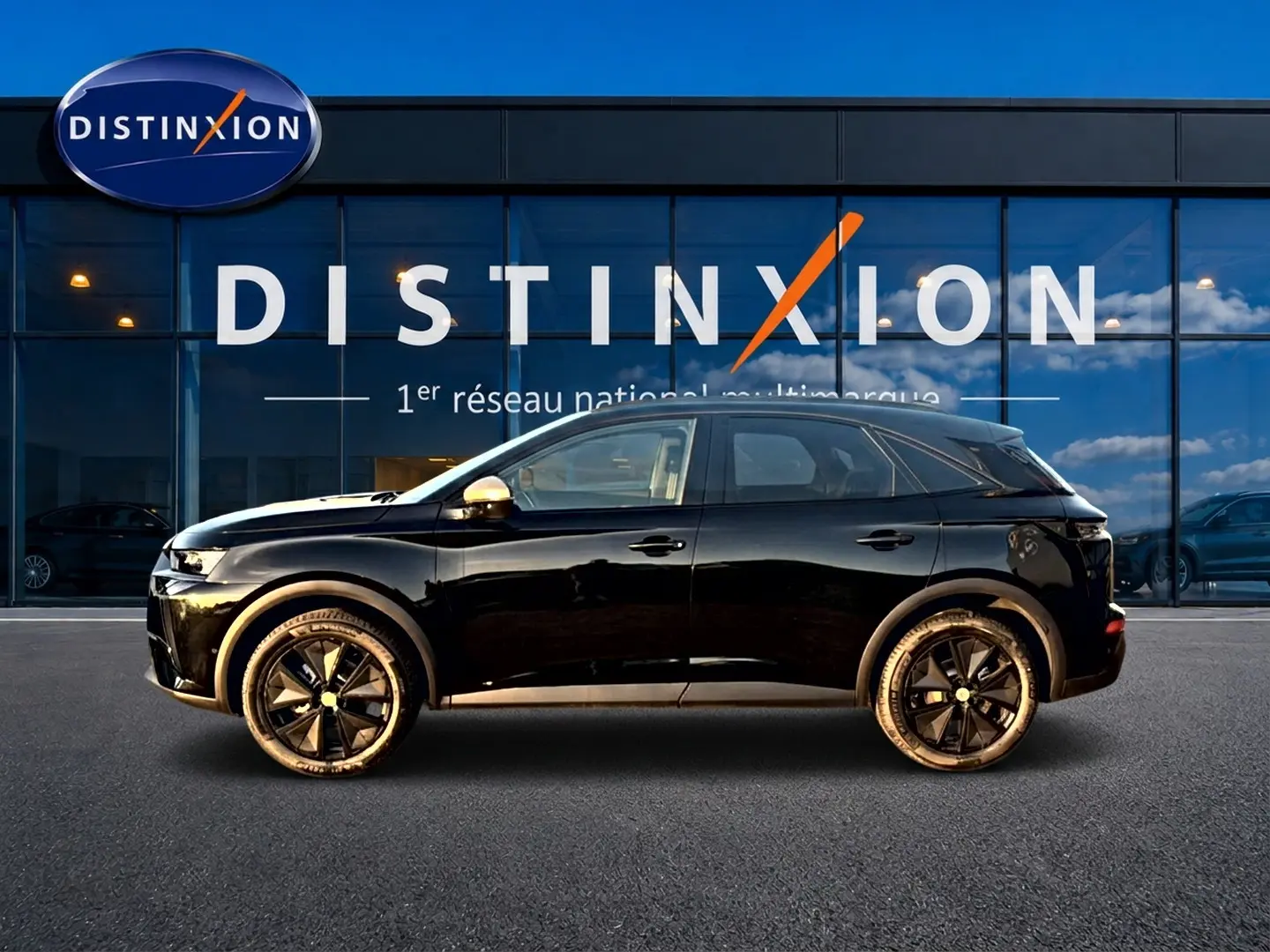Vue de profil côté gauche d'un DS7 noir 2026 avec jantes noires et rétroviseurs argentés devant une vitrine Distinxion.