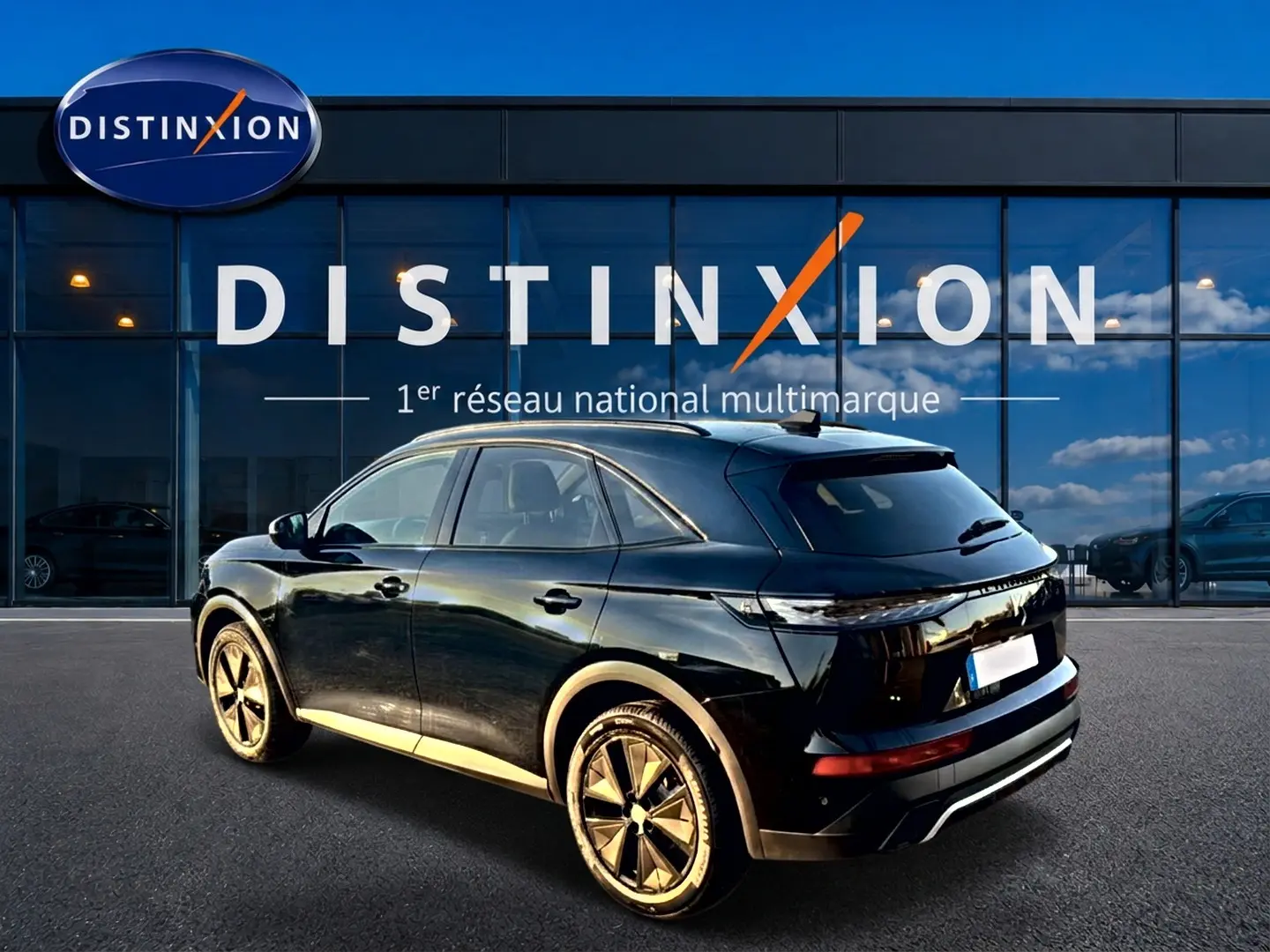 Vue 3/4 arrière droite du SUV DS7 noir brillant avec jantes alliage, garé devant une vitrine Distinxion.