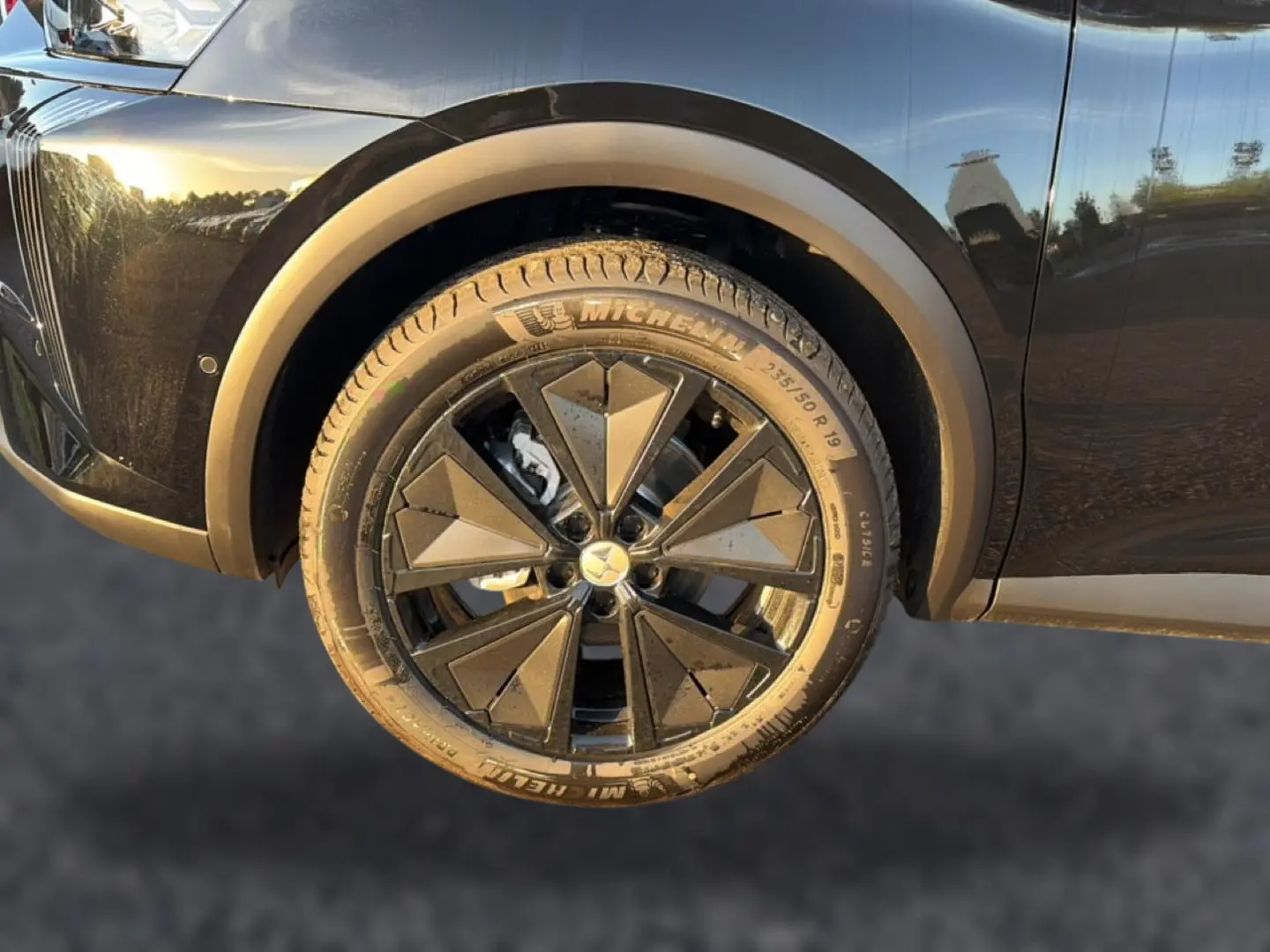 Gros plan sur la roue avant gauche noire du DS7 1.5 BlueHDi 130 Performance Line avec jante alu noire à motifs géométriques.