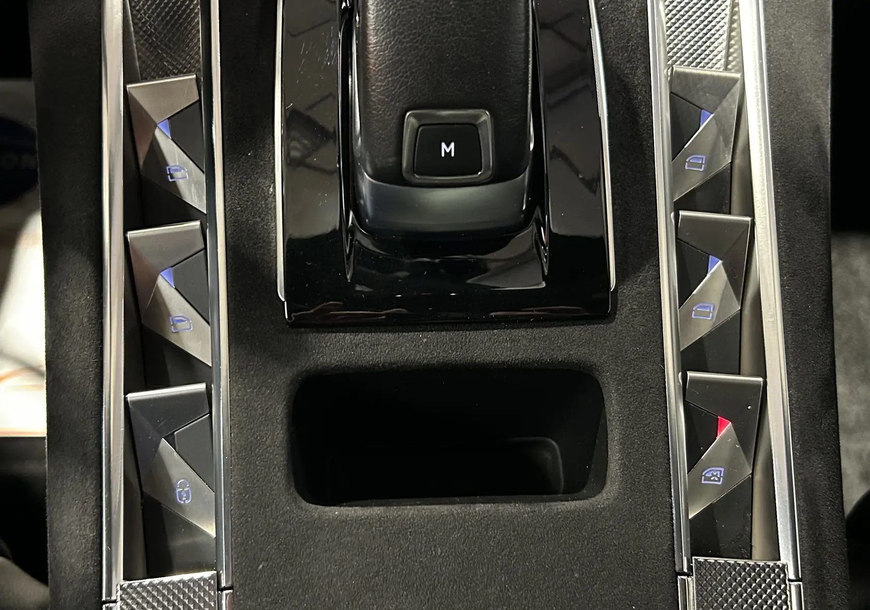 Vue rapprochée de la console centrale noire avec commandes de vitres et bouton "M" sur la DS7 Cristal Pearl 2024.