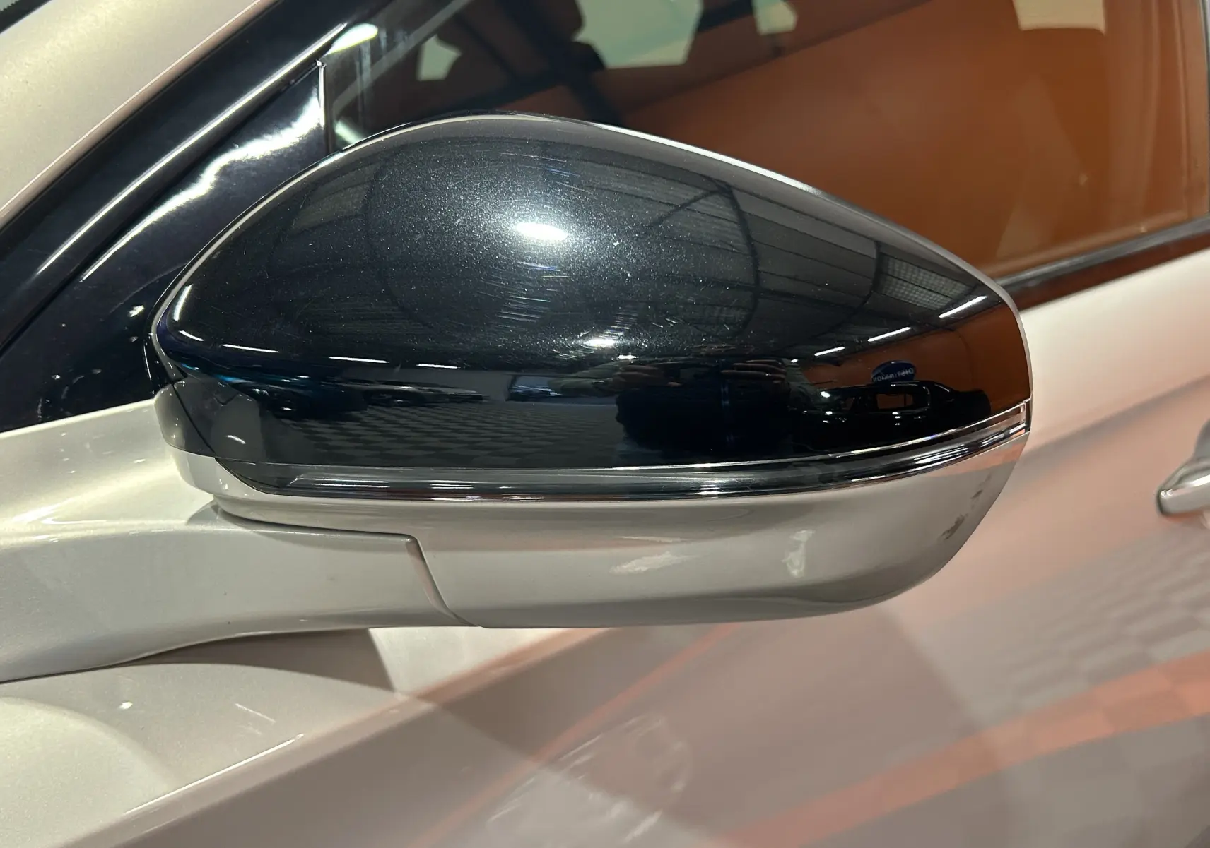 Gros plan sur le rétroviseur droit noir brillant du DS7 2024 couleur Cristal Pearl, soulignant son design élégant.