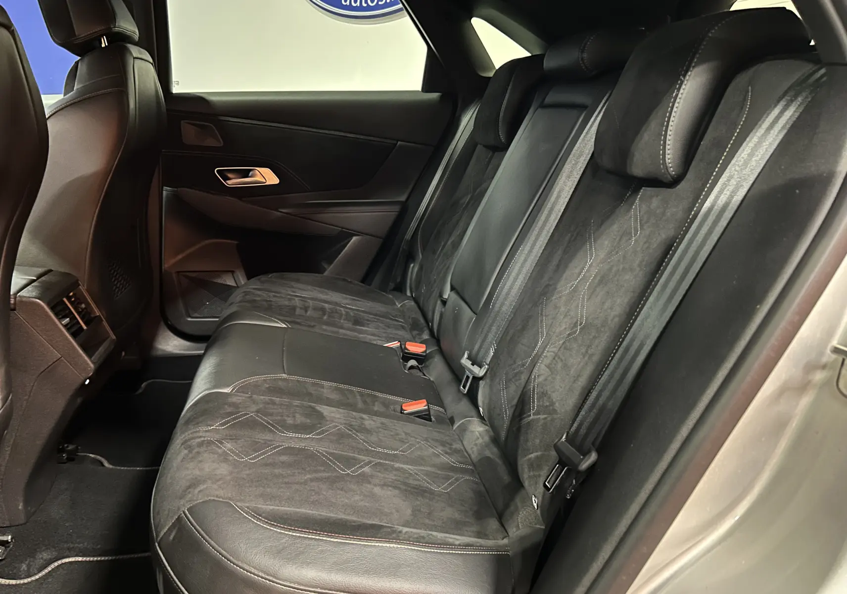Vue latérale droite de l'intérieur arrière du DS7 2024, sièges en cuir et alcantara noirs avec surpiqûres contrastées.