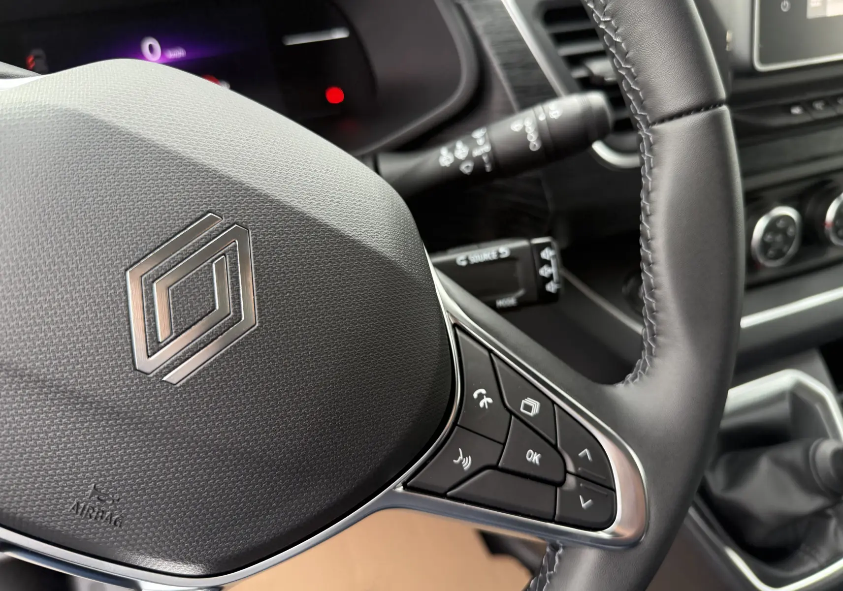 Gros plan sur le volant noir du Renault Trafic Combi 2025 avec commandes intégrées et tableau de bord partiellement visible.