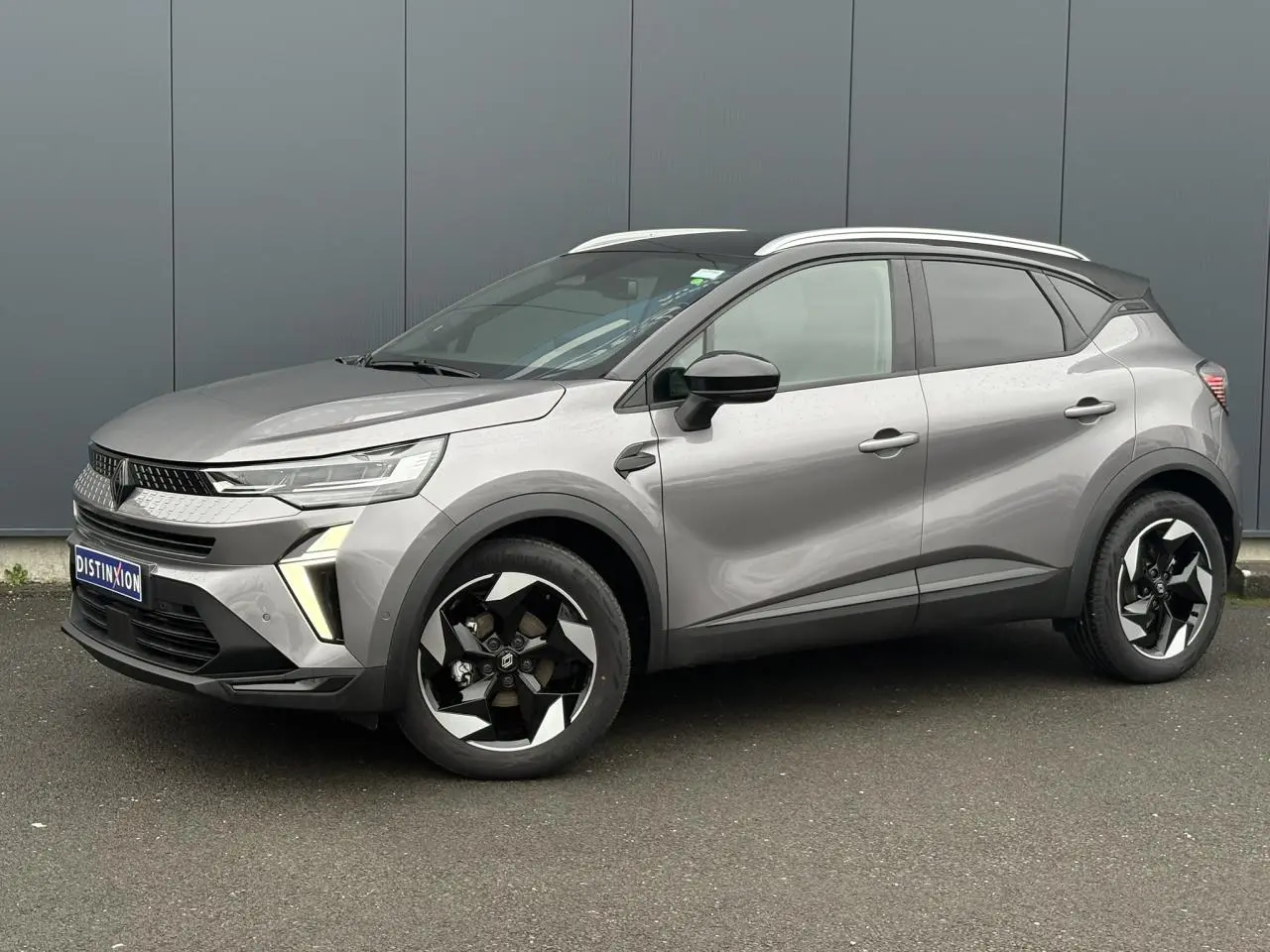 Renault Captur 2025 gris Cassiopée et noir, vue 3/4 avant droit avec jantes alu diamantées noires et railing de toit alu.