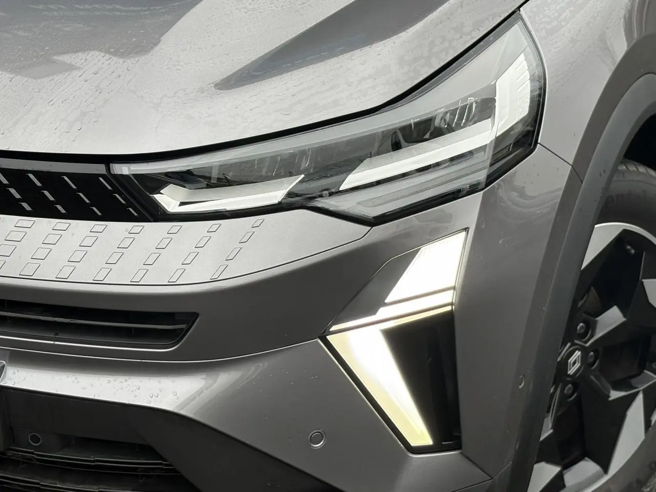 Gros plan sur l'avant droit du Renault Captur gris Cassiopée, mettant en valeur les phares LED et la jante alu noire diamantée.