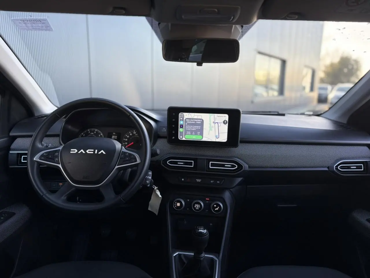 Vue intérieure frontale du tableau de bord du Dacia Jogger 2025 avec écran tactile GPS et volant noir multifonctions.