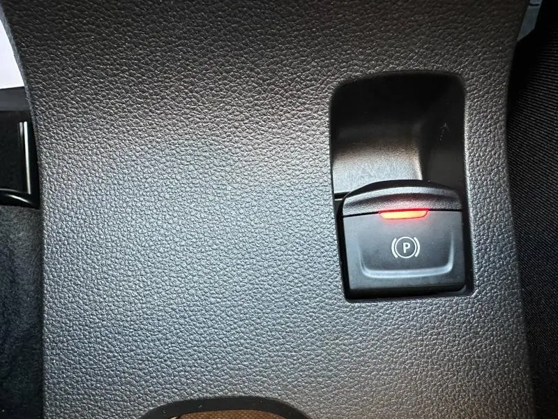 Bouton de frein de parking électronique éclairé en rouge sur tableau de bord noir du Dacia Sandero Stepway blanc 2025.
