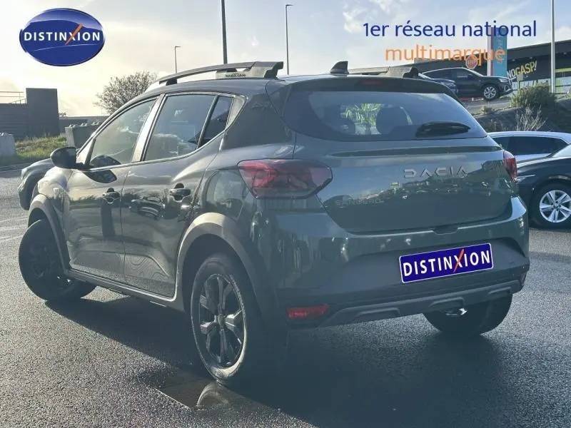 Vue 3/4 arrière droite d'une Dacia Sandero Stepway 2025 gris foncé avec jantes noires et toit noir contrasté.