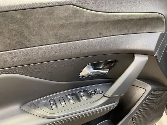 Détail de la porte avant gauche de la Peugeot 308 Hybrid 145 e-DCS6 GT blanche, avec commandes électriques et garniture mixte cuir et alcantara.