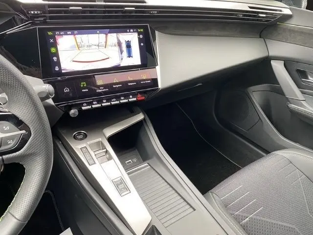 Vue intérieure côté passager de la Peugeot 308 Hybrid 145 e-DCS6 GT 2026, avec écran tactile central et console moderne noire.
