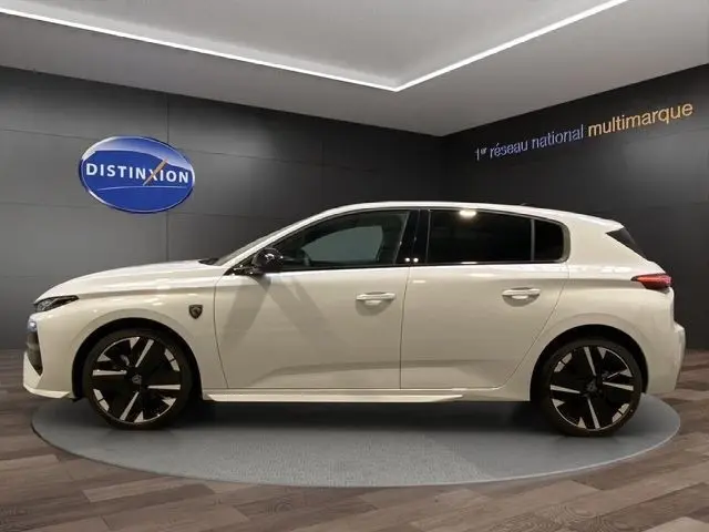 Vue de profil côté gauche d'une Peugeot 308 Hybrid 145 e-DCS6 GT blanche, roues noires au design moderne, en showroom.