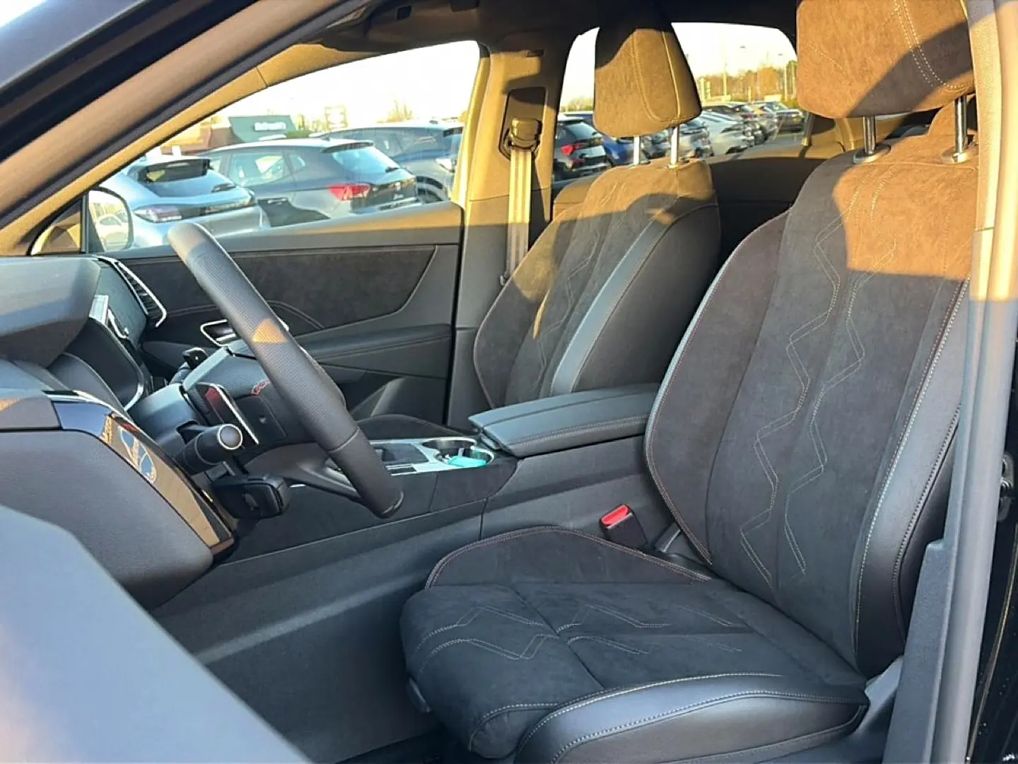 Intérieur côté conducteur du DS7 noir, montrant sièges en alcantara avec surpiqûres et accoudoir central.
